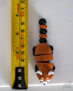 Red panda viewed from above next to measuring tape for scale