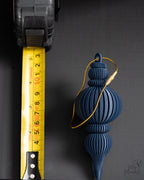 blue modern ribbed christmas bauble next to measuring tape for scale