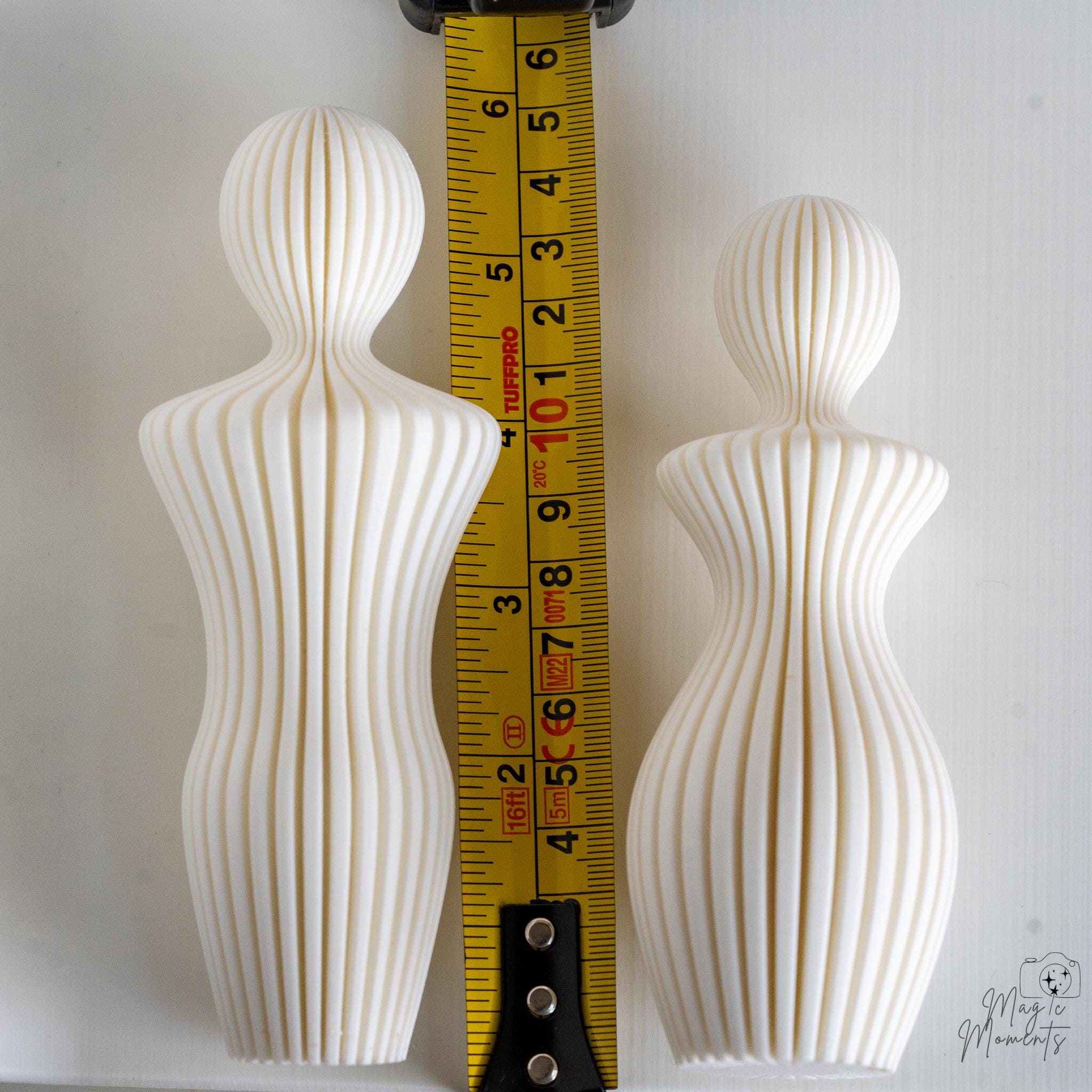 White couple sculpture next to measuring tape for scale