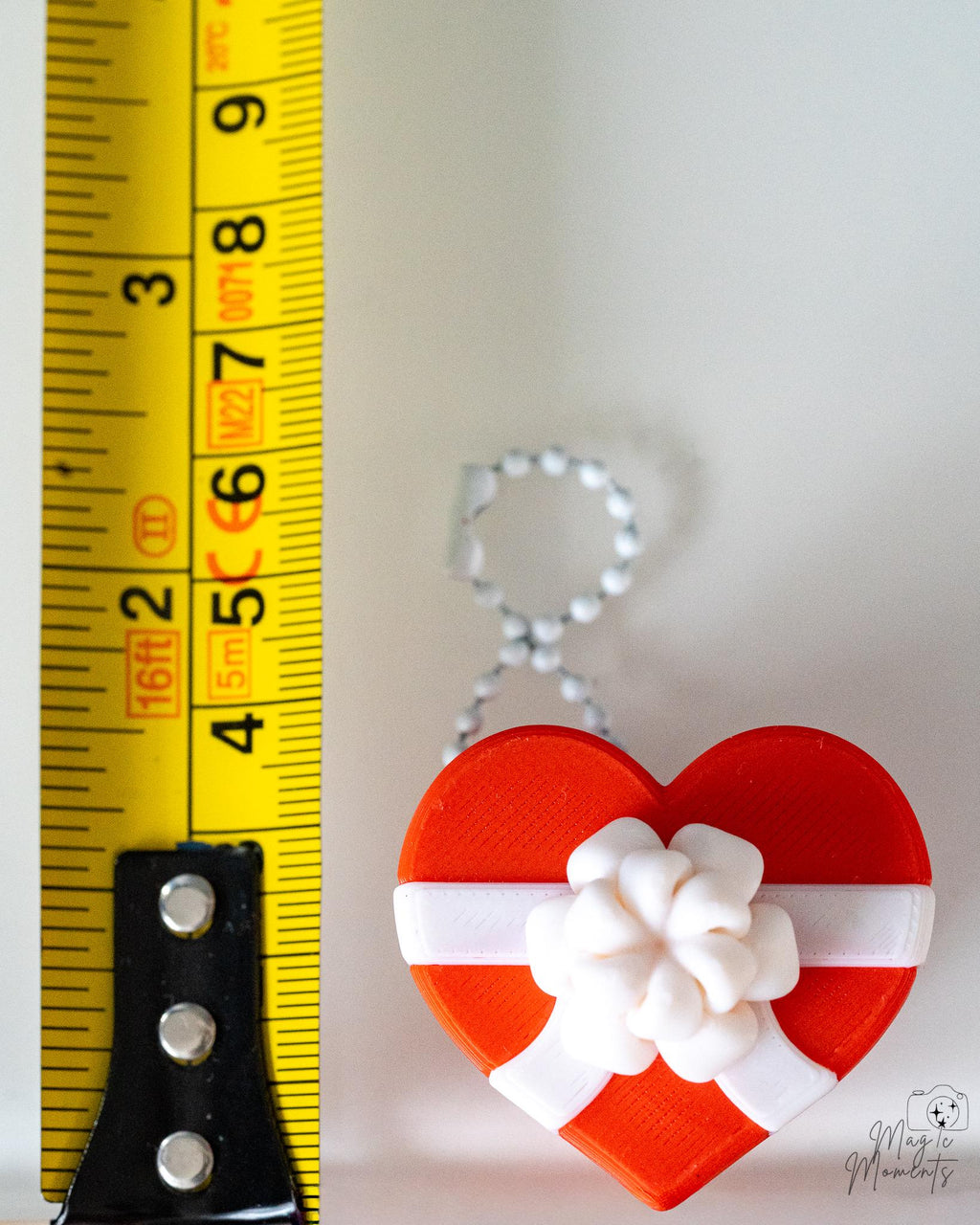 heart clicker ornament next to measuring tape for scale