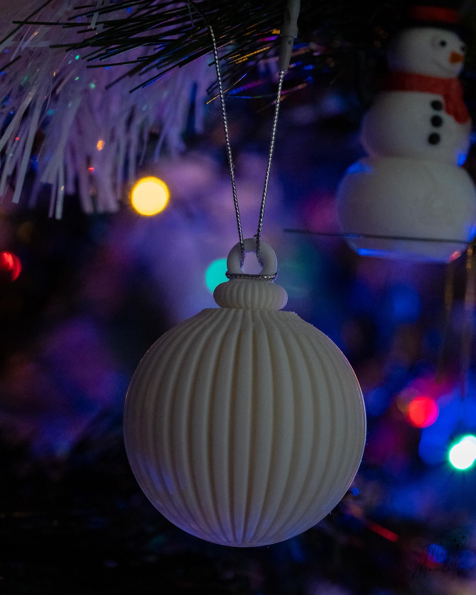 White Christmas bauble hanging on decorated Christmas tree