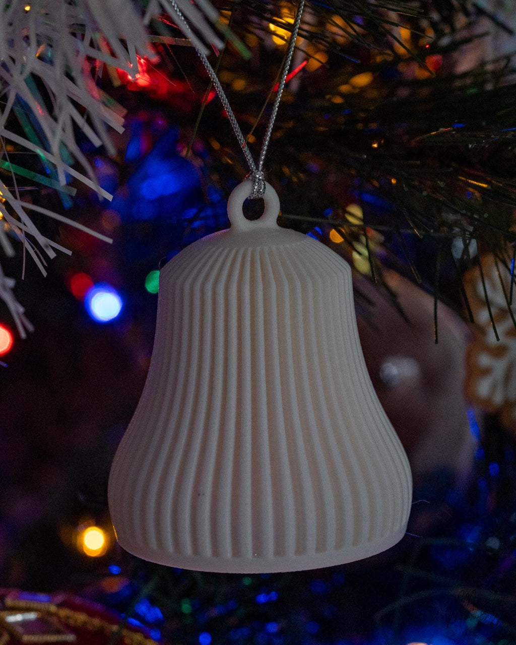 white christmas bell ornament next to measuring tape for scale