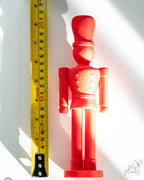 red nutcracker decoration next to measuring tape for scale