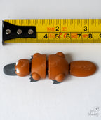 platypus figurine next to a yellow measuring tape for a scale