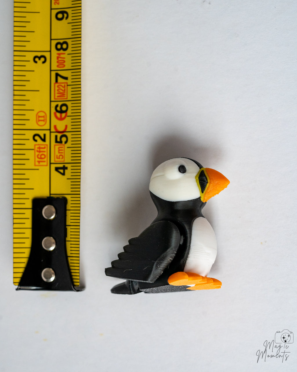 Puffin figurine next to a measuring tape on a white background