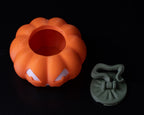 Orange pumpkin-shaped container with white accents on a black background