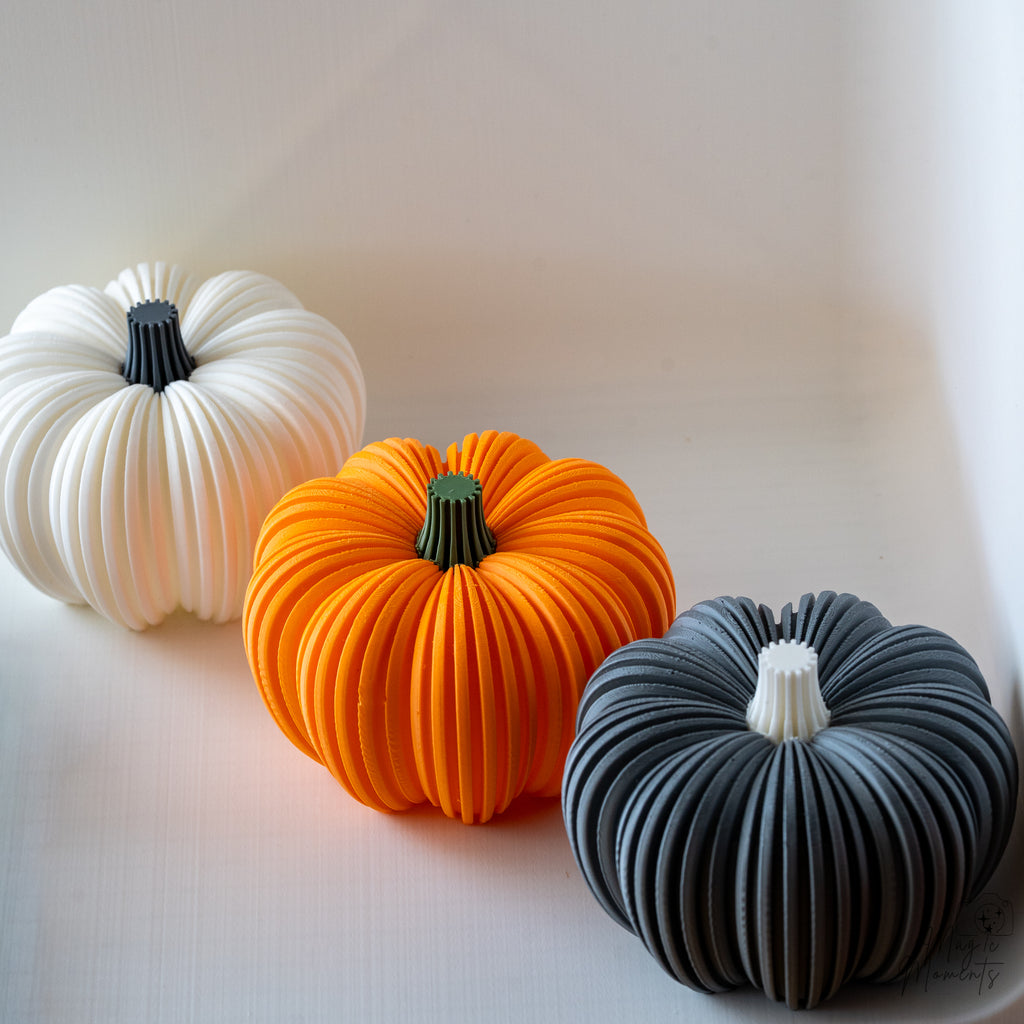 Three textured pumpkin in white, orange, and grey on a light background