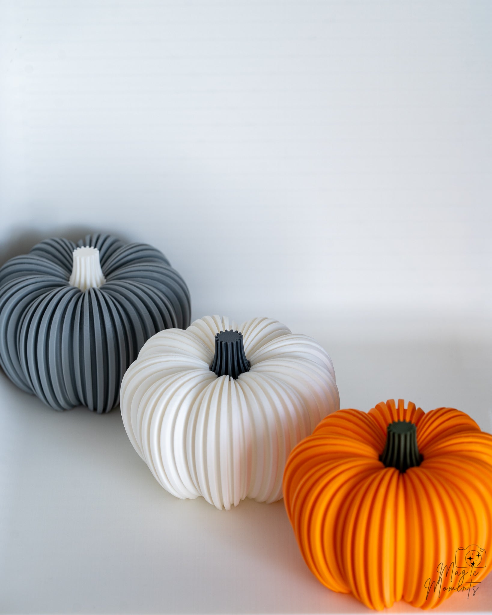 Three ribbed pumpkin in grey, white, and orange on a light background