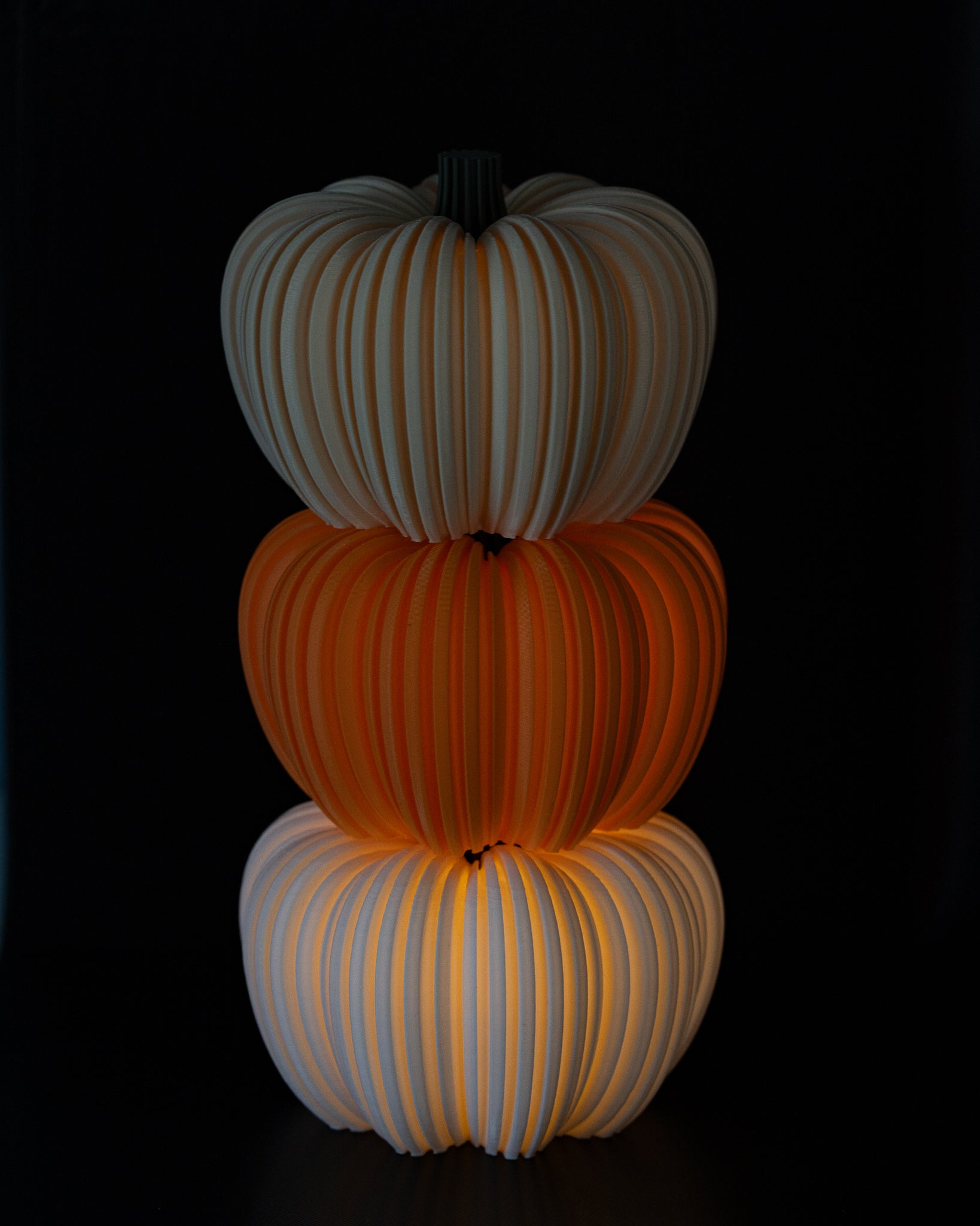Stack of three glowing pumpkins on a black background