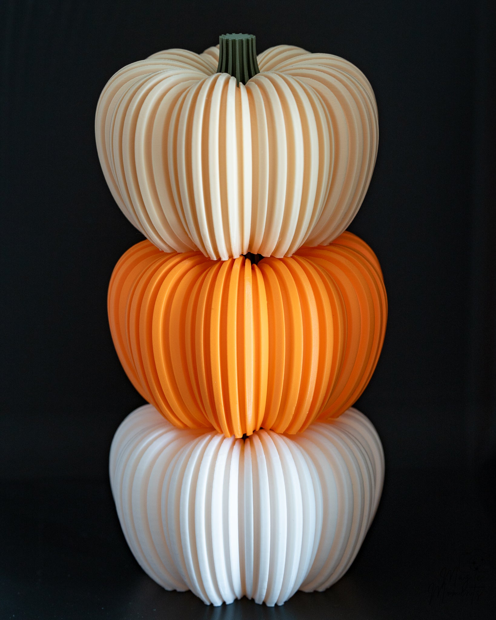 Three stacked pumpkins in orange, white, and beige on a black background