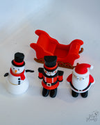 Christmas-themed figurines including a snowman, soldier, and Santa Claus on a white background.
