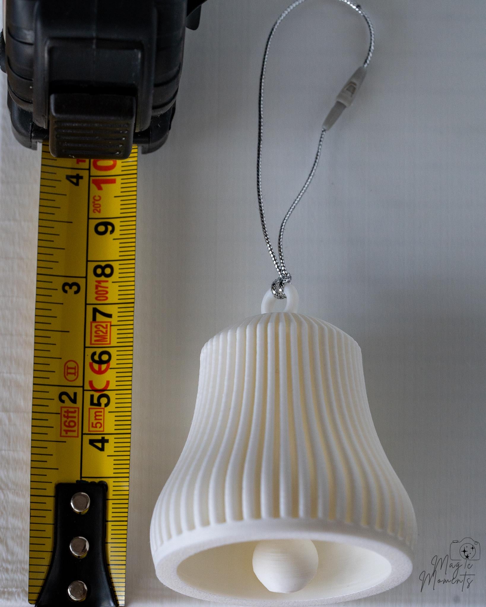 white ribbed christmas bell ornament next to measuring tape for scale