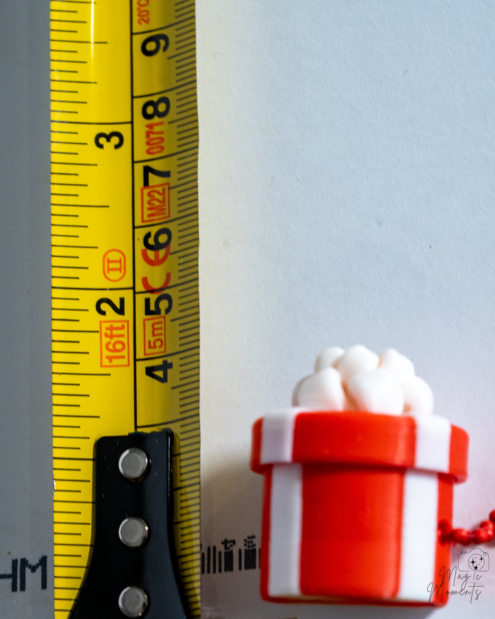 red striped christmas gift clicker next to measuring tape for scale