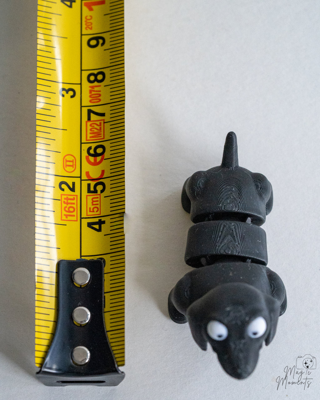 Black dog figure next to measuring tape for scale