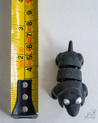 Black dog figure next to measuring tape for scale