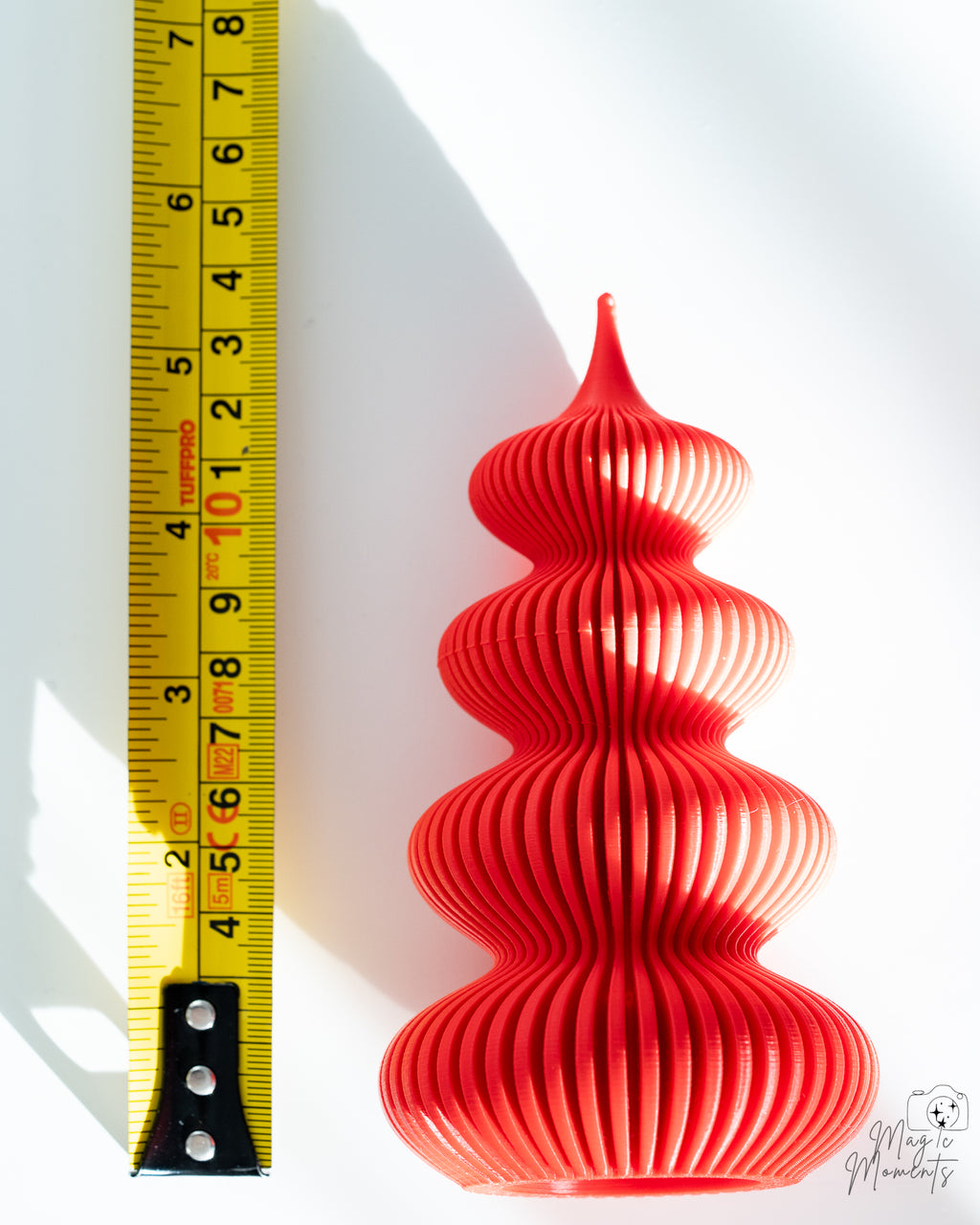 Red Christmas tree decoration next to measuring tape for scale