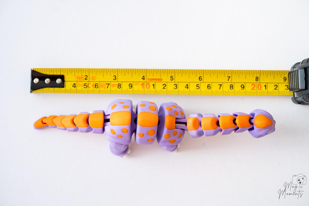 3D printed articulated dinosaur next to measuring tape for scale