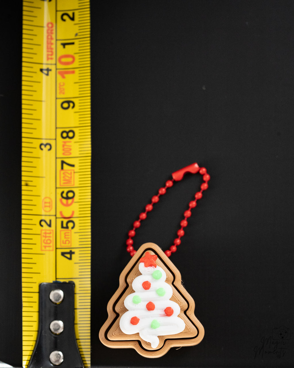 christmas tree gingerbread clicker keychain next to measuring tape for scale