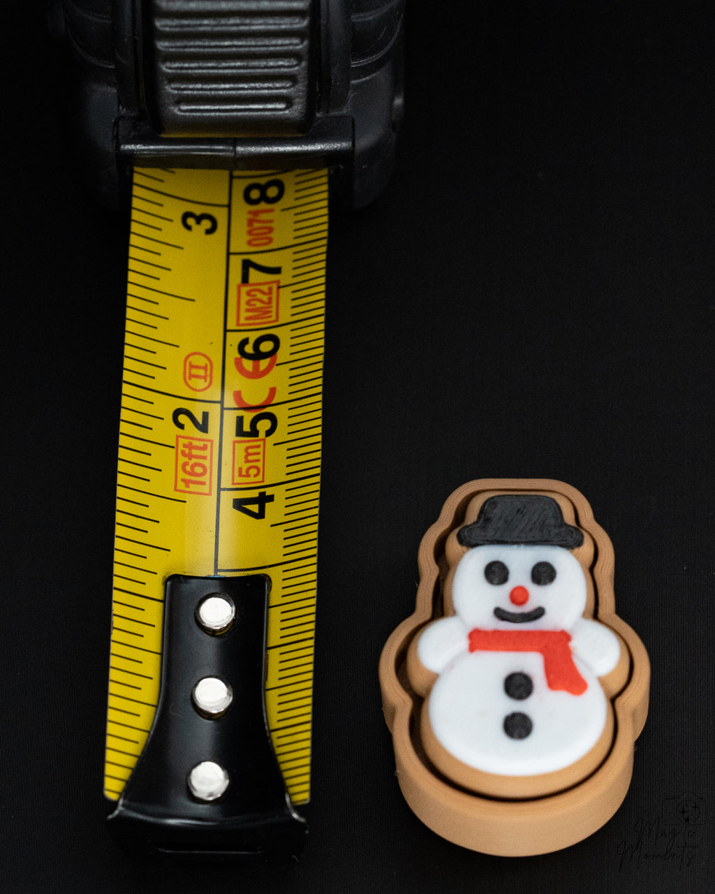 snowman cookie gingerbread clicker keychain next to measuring tape for scale