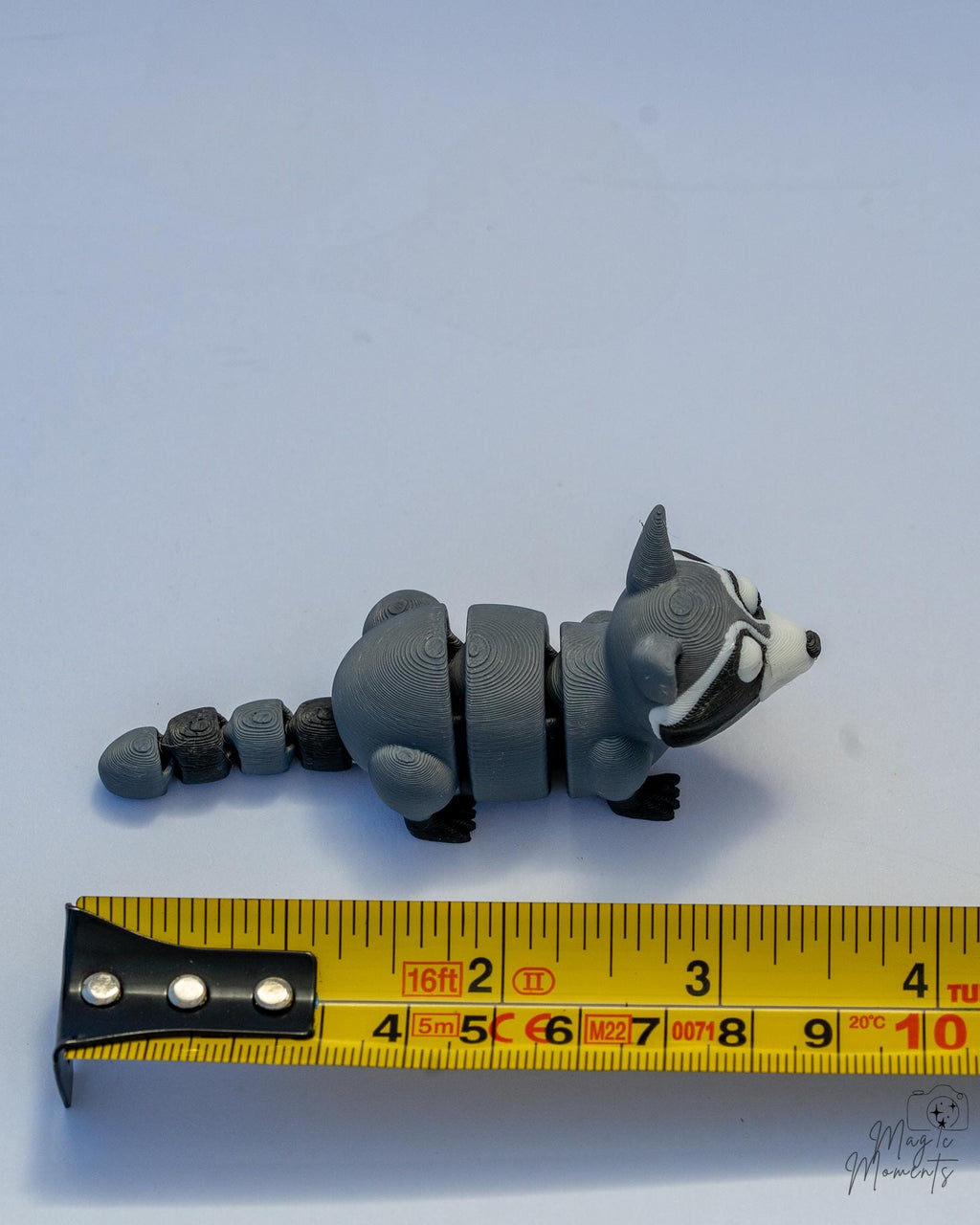 raccoon figurine next to measuring tape for scale
