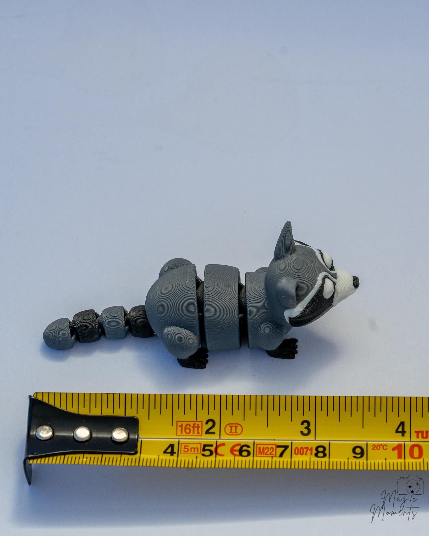 raccoon figurine next to measuring tape for scale