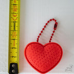 Heart clicker keychain next to measuring tape for scale