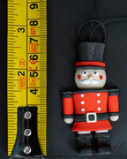 Small nutcracker ornament next to measuring tape for scale