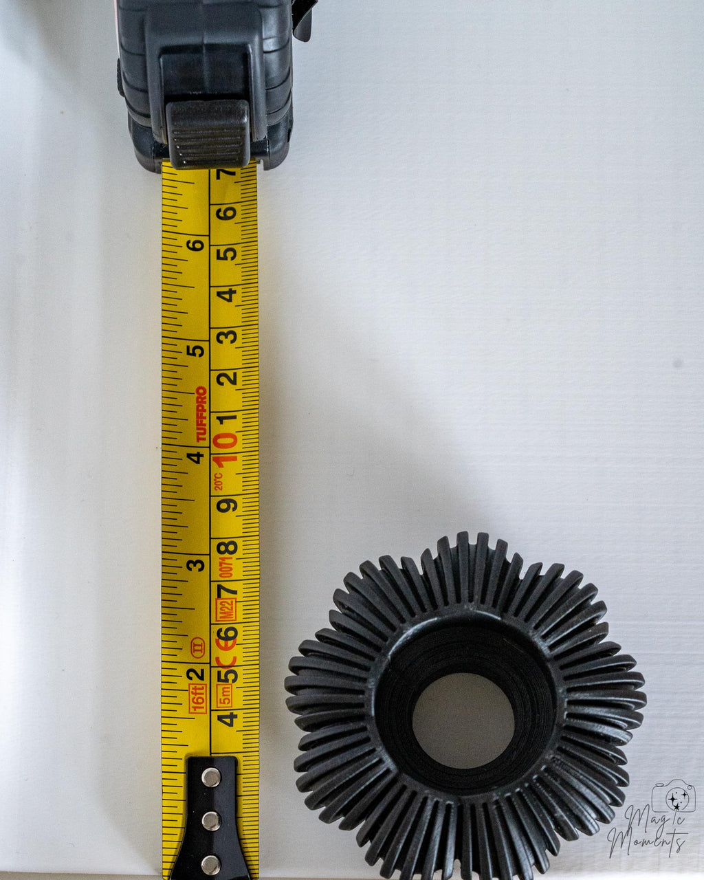 Grey pumpkin tealight holder viewed from above next to measuring tape for scale