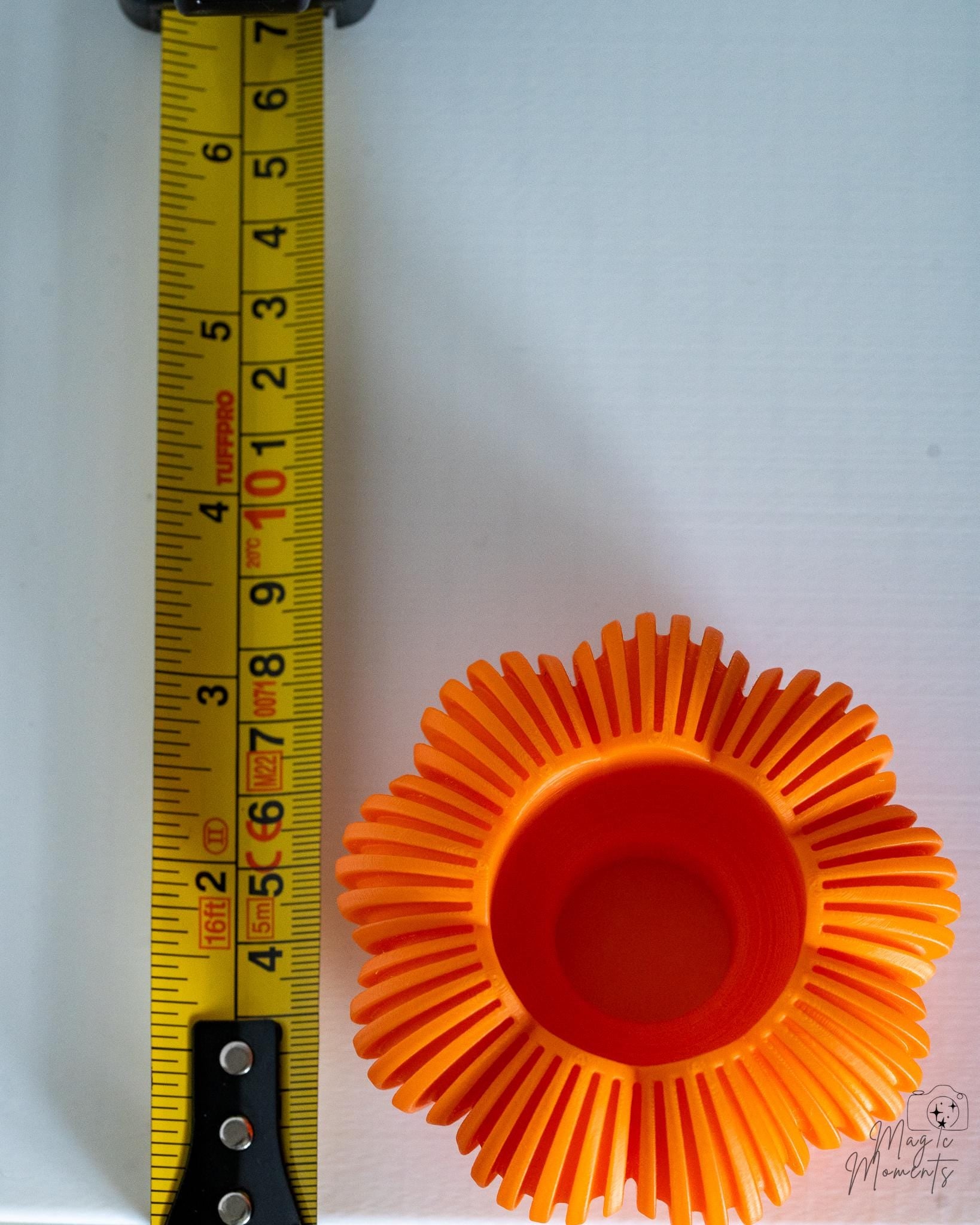 Orange pumpkin tealight holder viewed from above next to measuring tape for scale