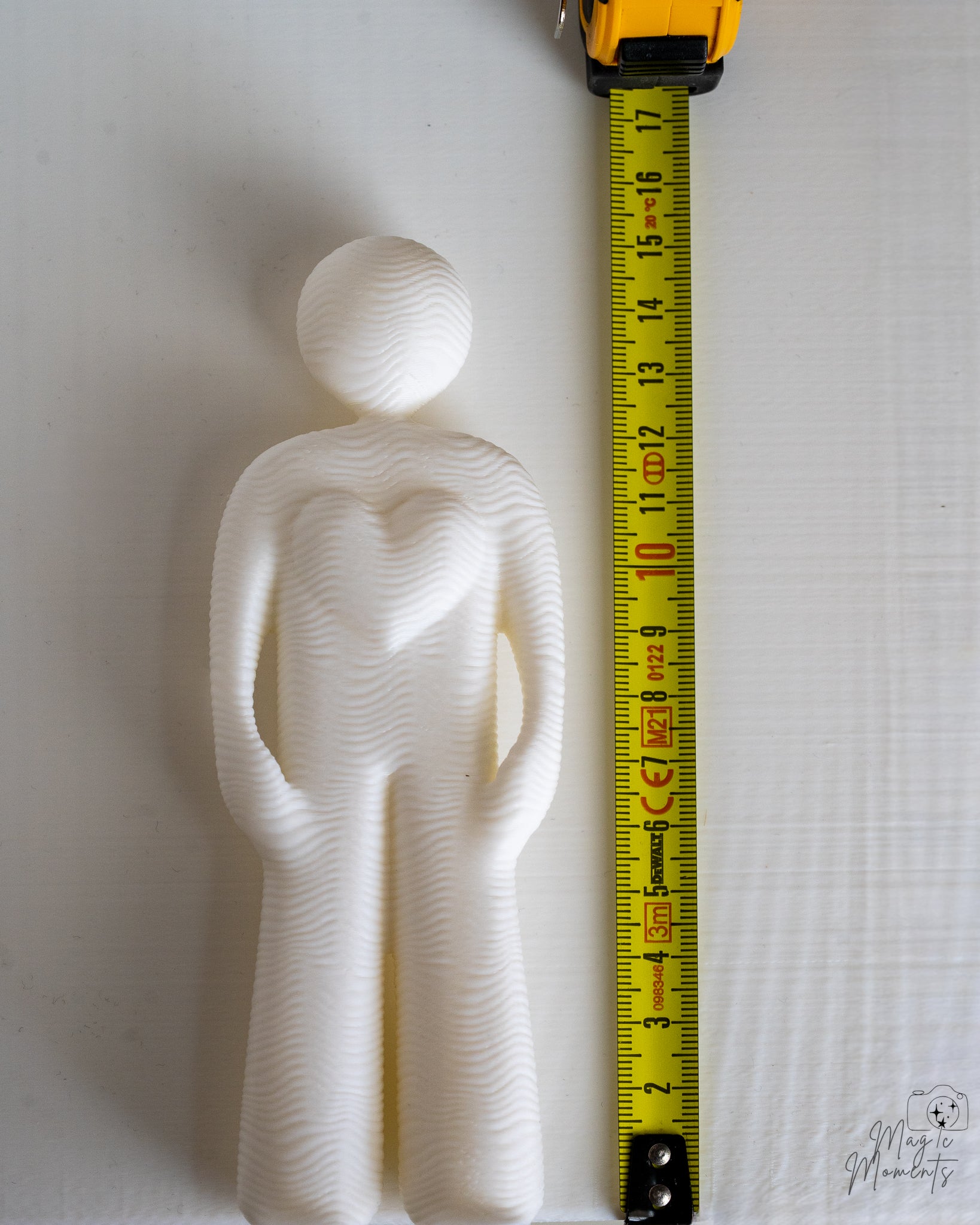white decor figure next to measuring tape for scale