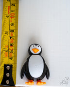 Penguin figure next to measuring tape for scale