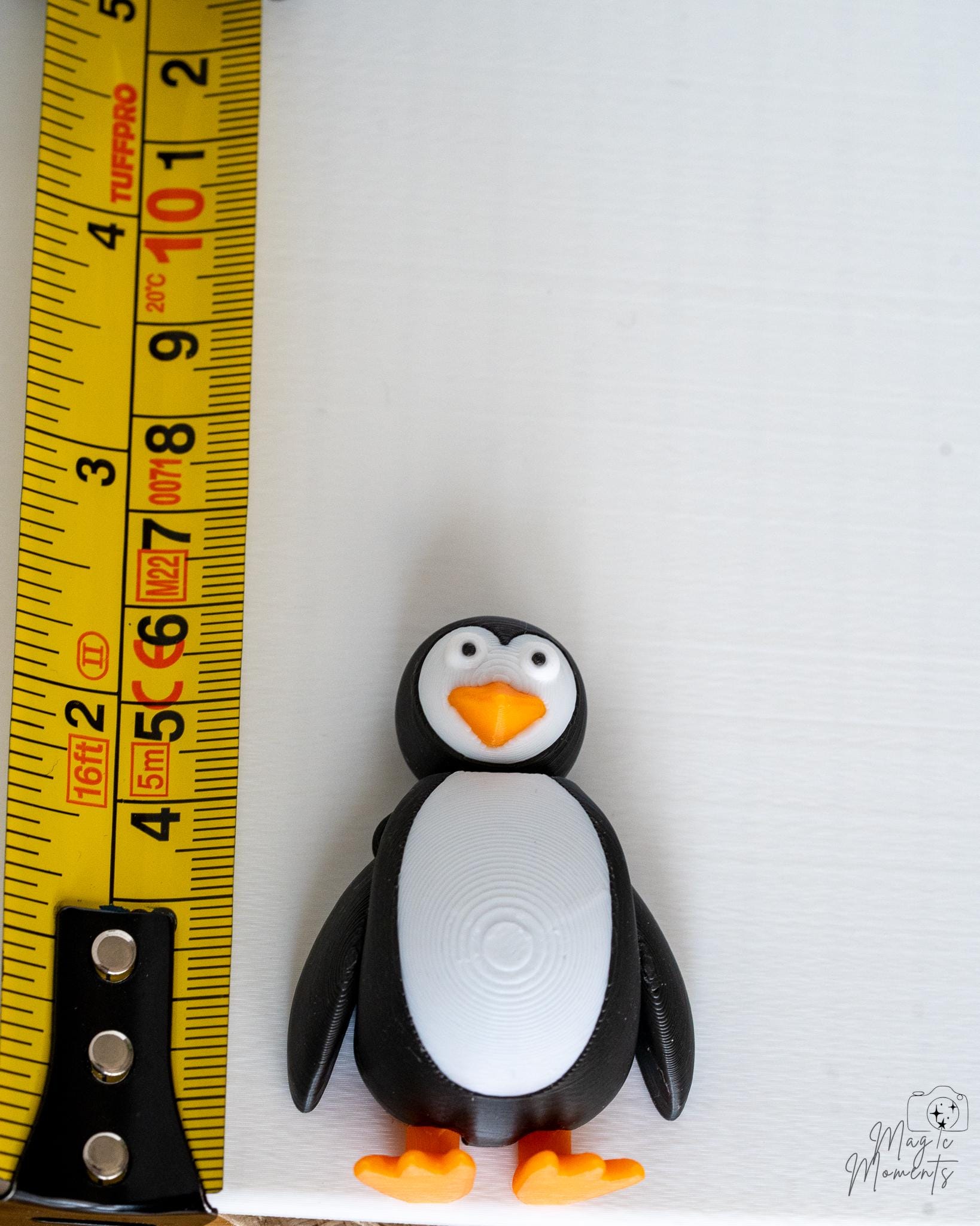Penguin figure next to measuring tape for scale