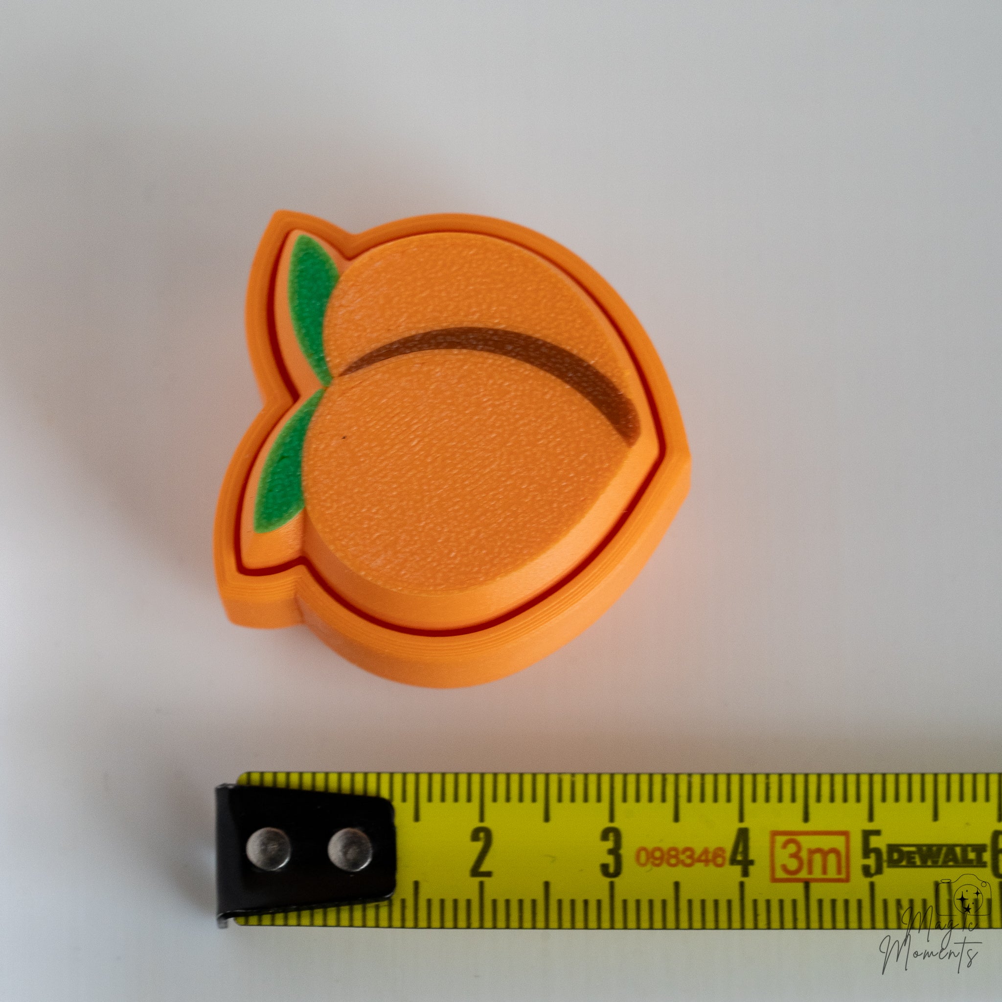 peach keychain next to measuring tape for scale