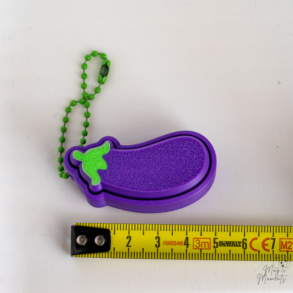 eggplant keychain next to measuring tape for scale