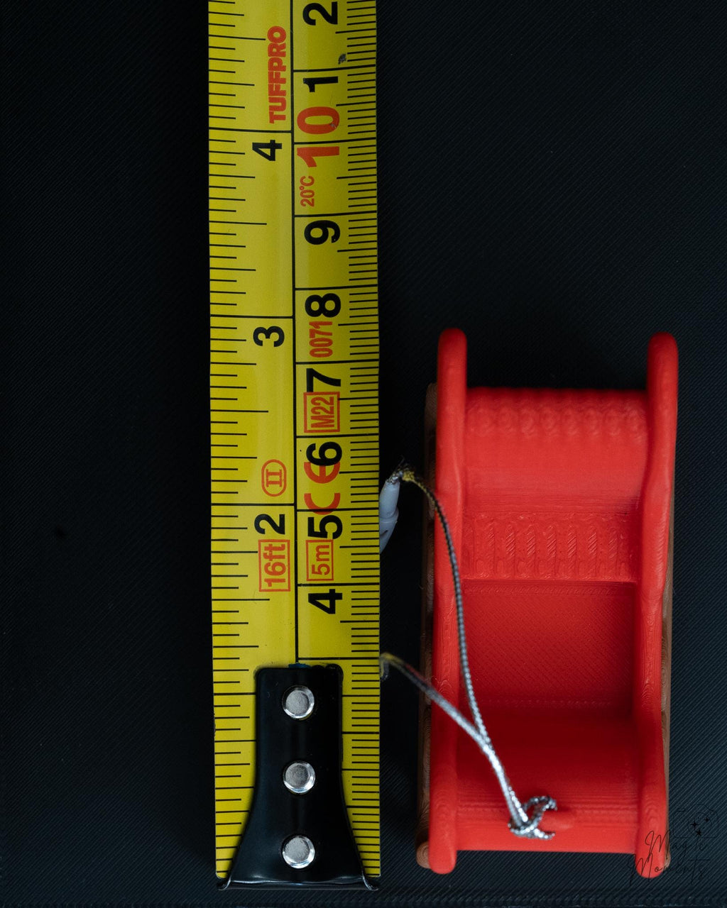 Mini Christmas sleigh ornament with hanging loop next to measuring tape for scale