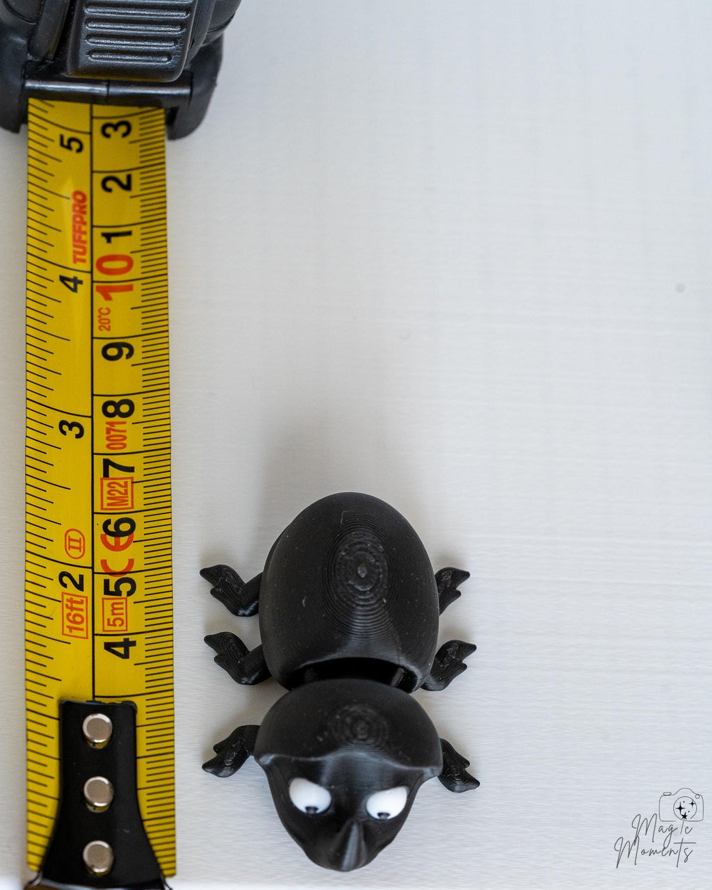 Beetle figure next to measuring tape for scale