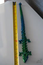 Flexible segmented dragon with blue and green crystal egg next to measuring tape for scale