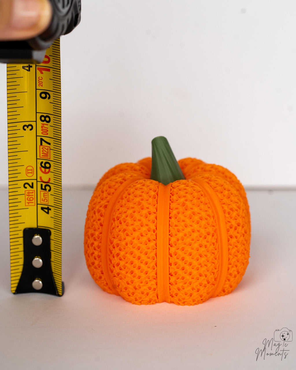 Mesh pumpkin candle holder for Halloween decor next to measuring tape for scale