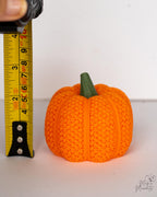 Mesh pumpkin candle holder for Halloween decor next to measuring tape for scale