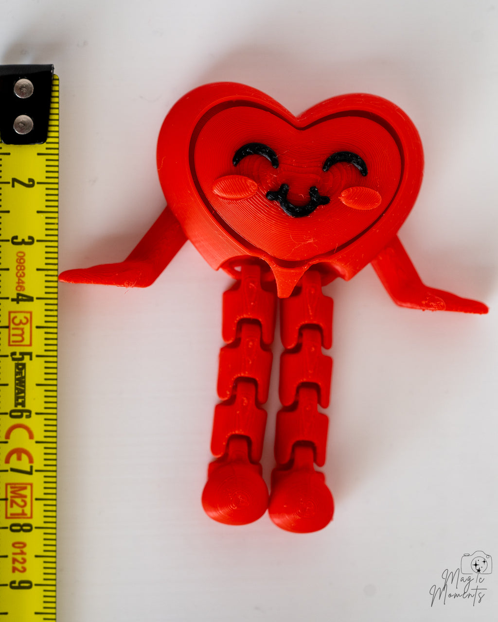 Smiling heart clicker decorative figure next to measuring tape for scale