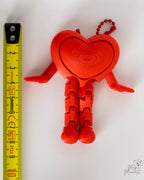 Heart clicker keychain next to measuring tape for scale