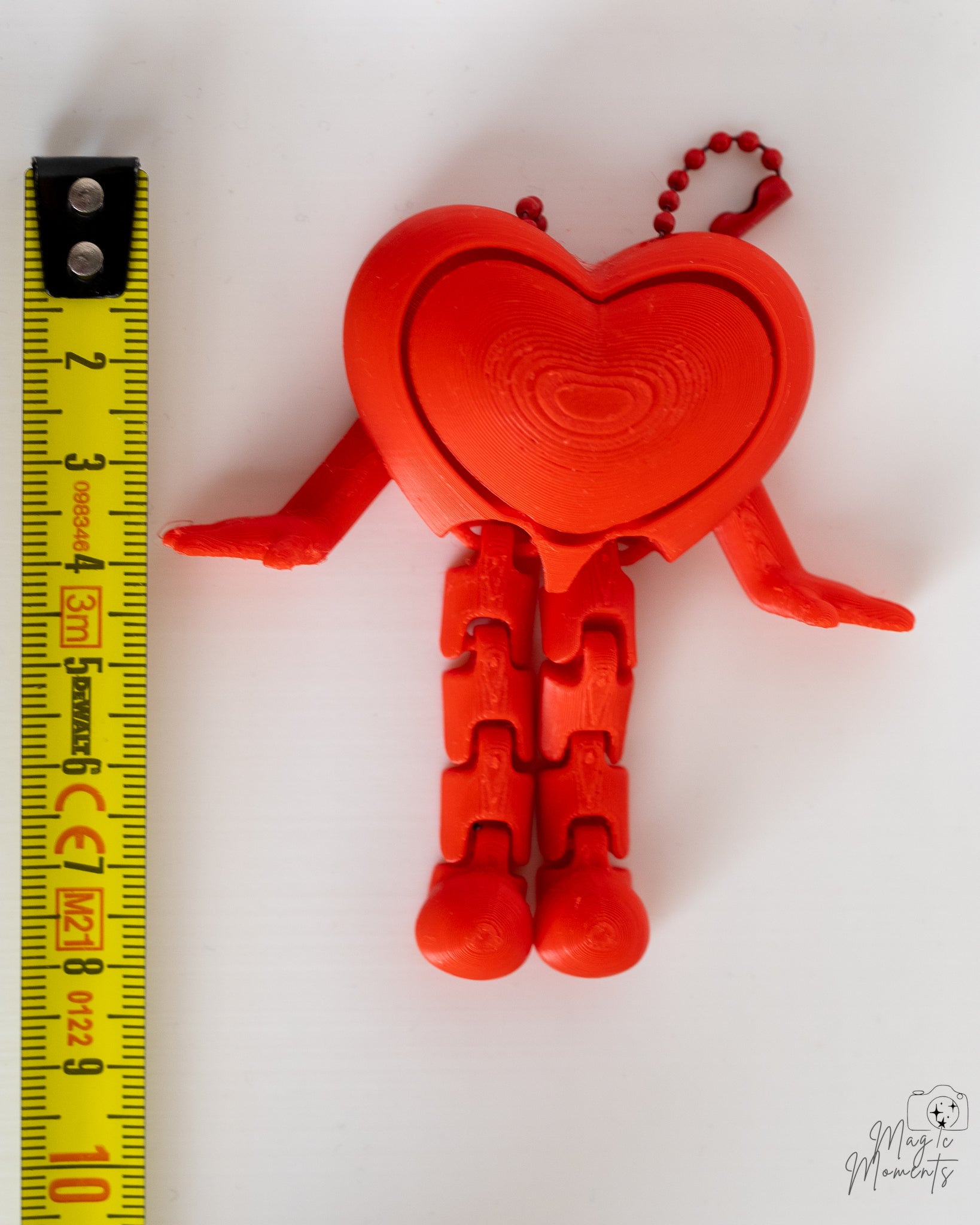Heart clicker keychain next to measuring tape for scale