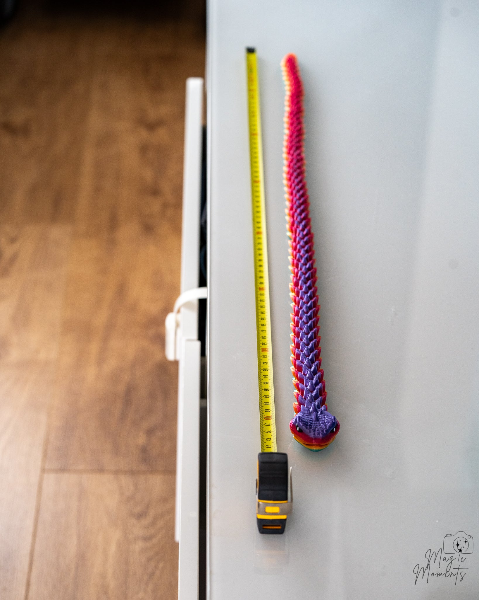 Rainbow articulated snake next to measuring tape for scale