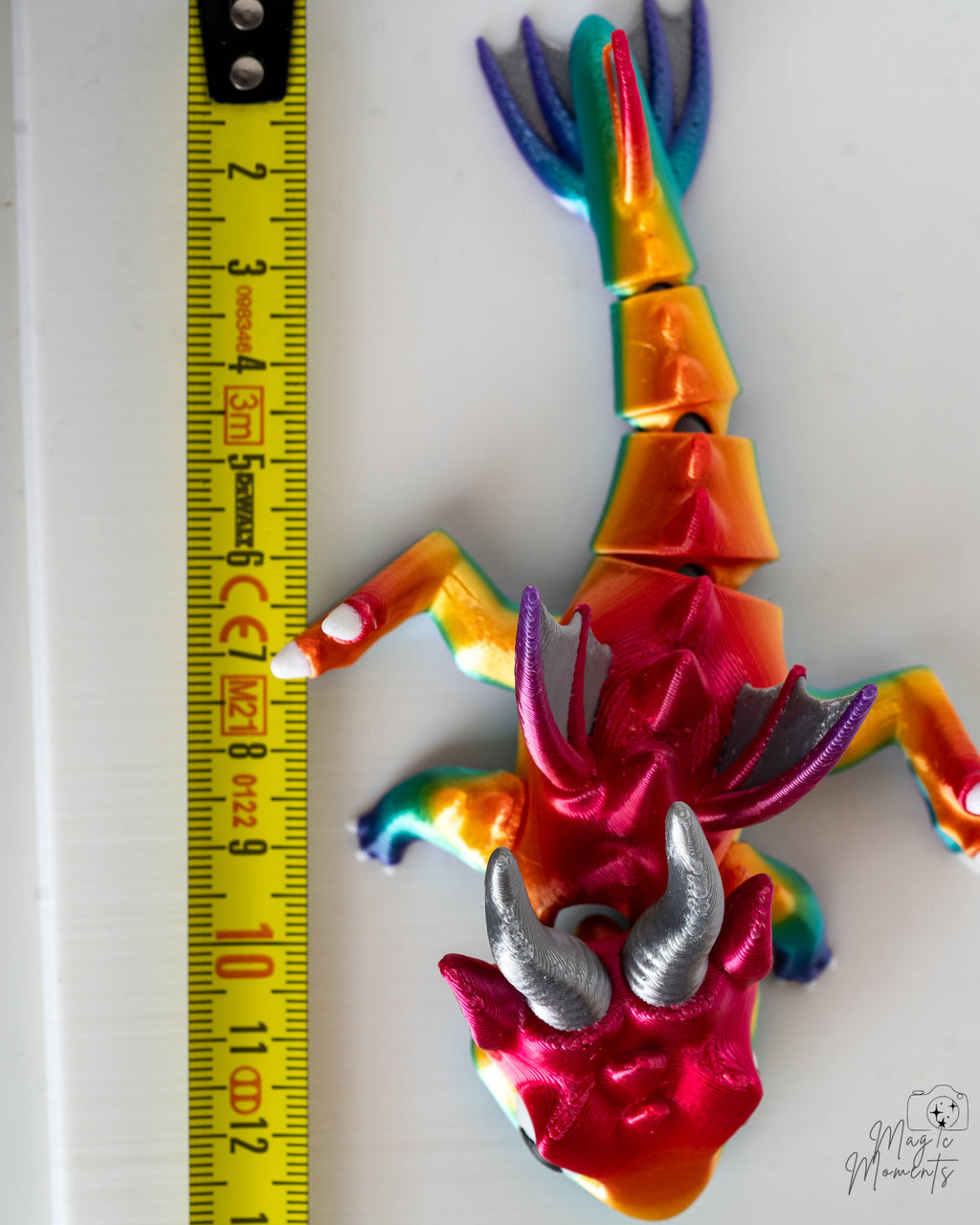 Rainbow dragon figure next to measuring tape for scale