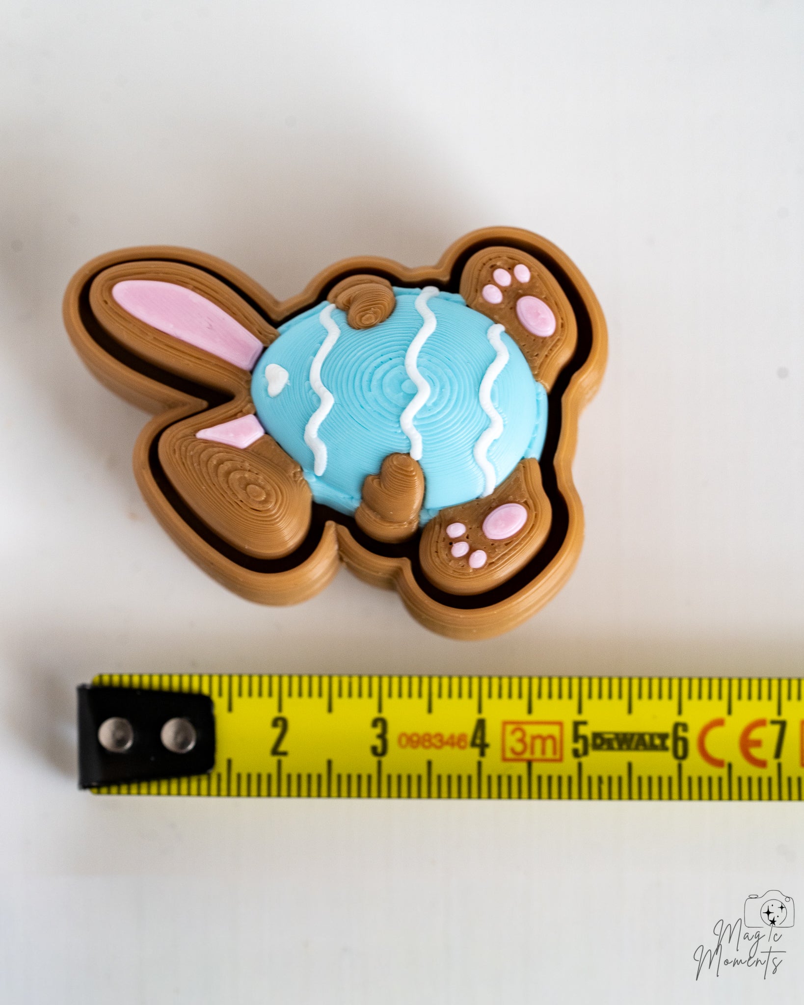 Blue bunny clicker viewed from above next to measuring tape for scale