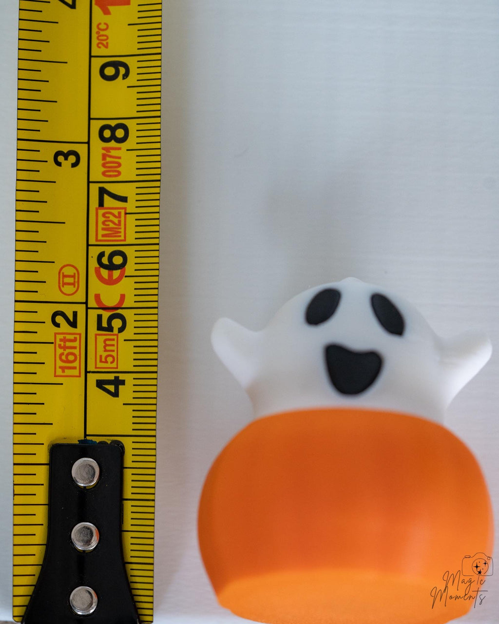 Ghost pumpkin figure with surprised face next to measuring tape for scale