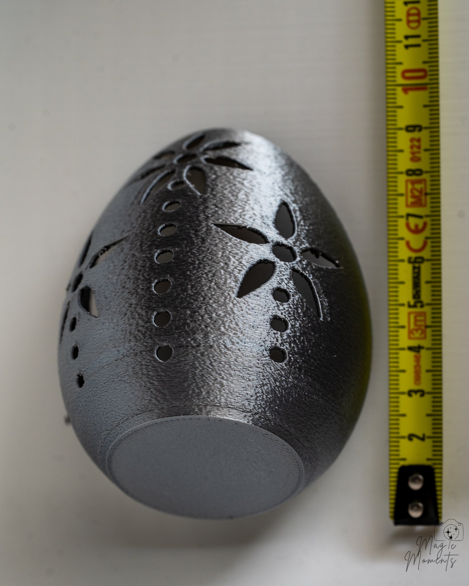 Silver decorative egg candle holder next to measuring tape for scale