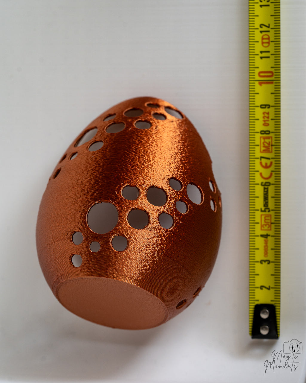 Metallic bronze Easter egg tealight holder next to measuring tape for scale