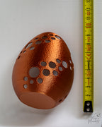 Metallic bronze Easter egg tealight holder next to measuring tape for scale