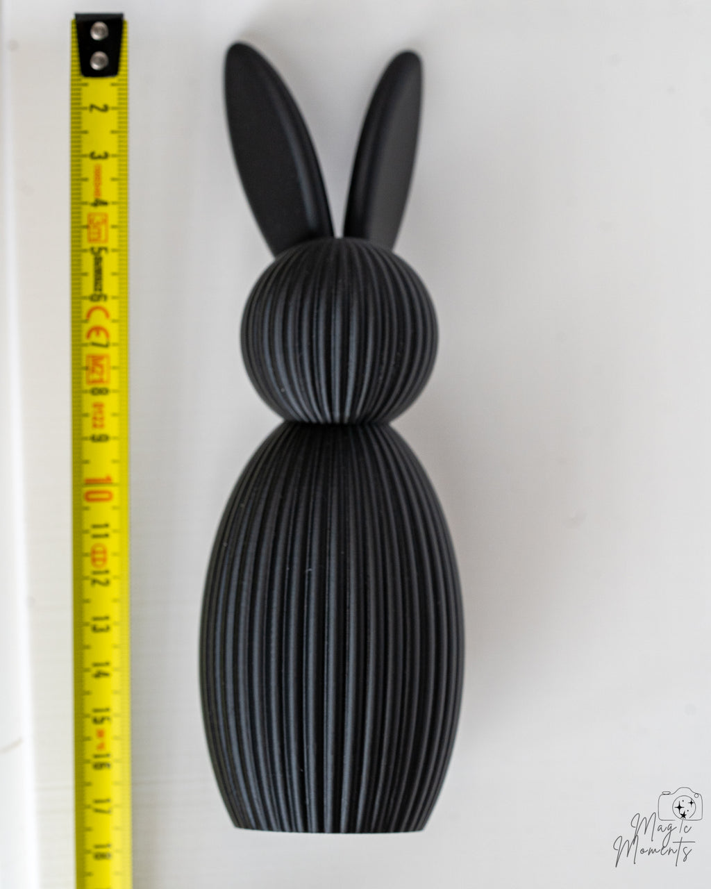 Black bunny figure next to measuring tape for scale